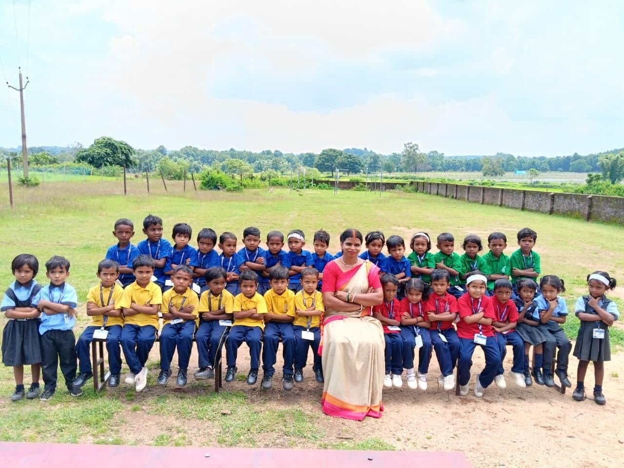 Early years pupils seated in rows with their teacher on the school ground