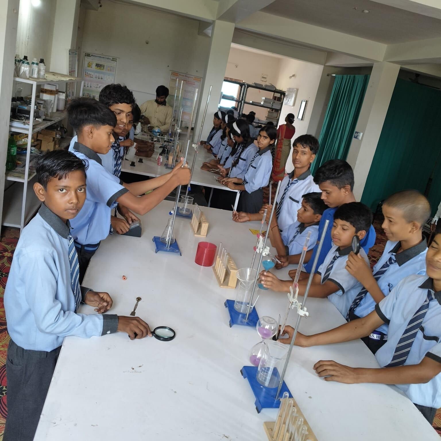 Students carrying out an experiment with stands, test tubes and magnifying glasses in the science lab