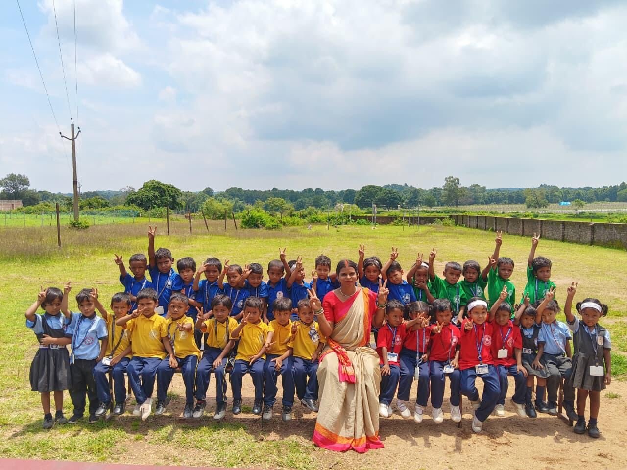 Young RGS students cheering with their teacher on the school ground
